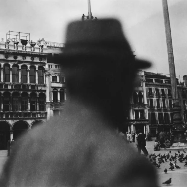 Uomo con cappello, in piedi davanti a un edificio.